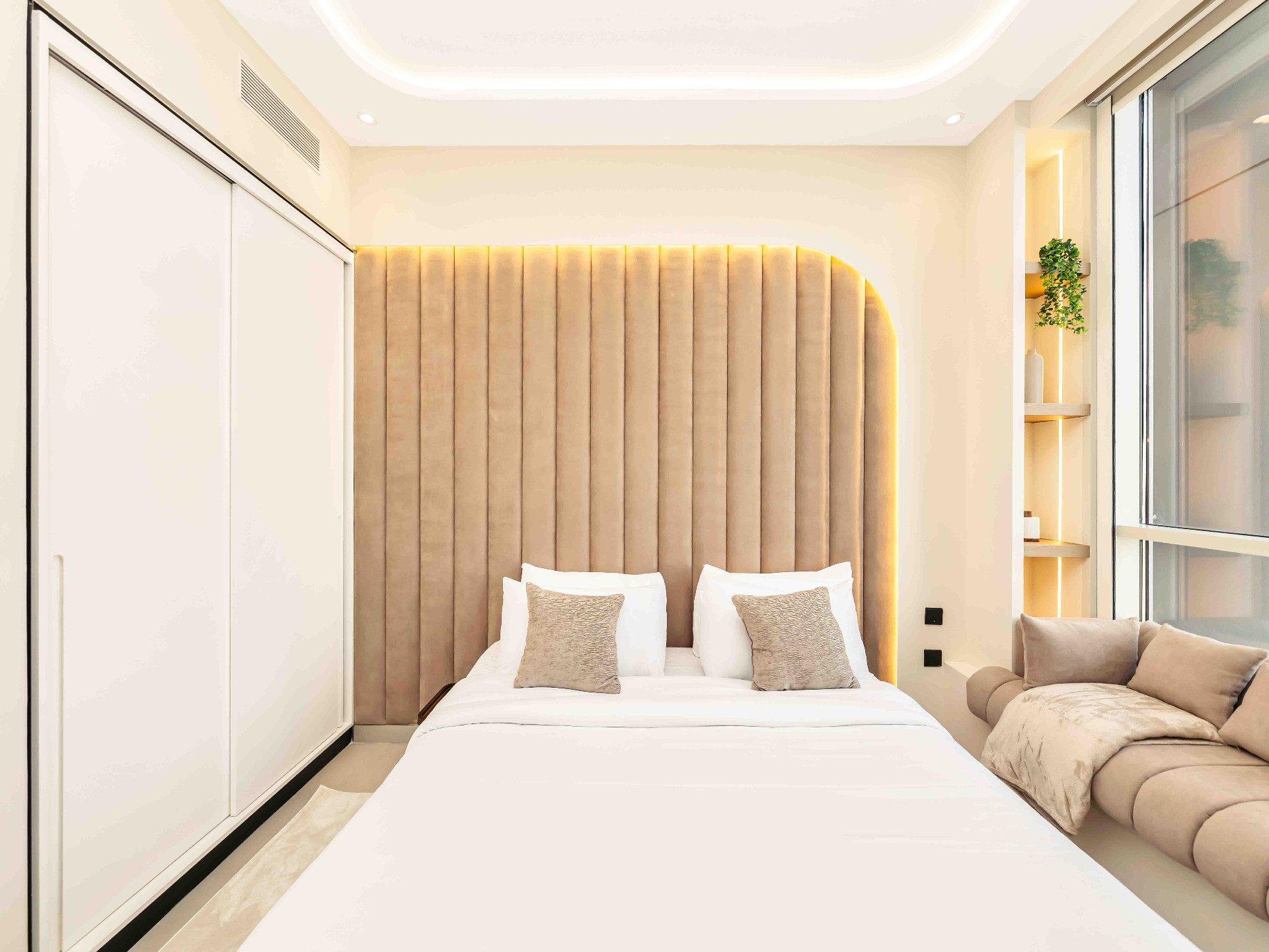 Bedroom with arched fluted headboard, white sliding wardrobe and recessed shelving niche