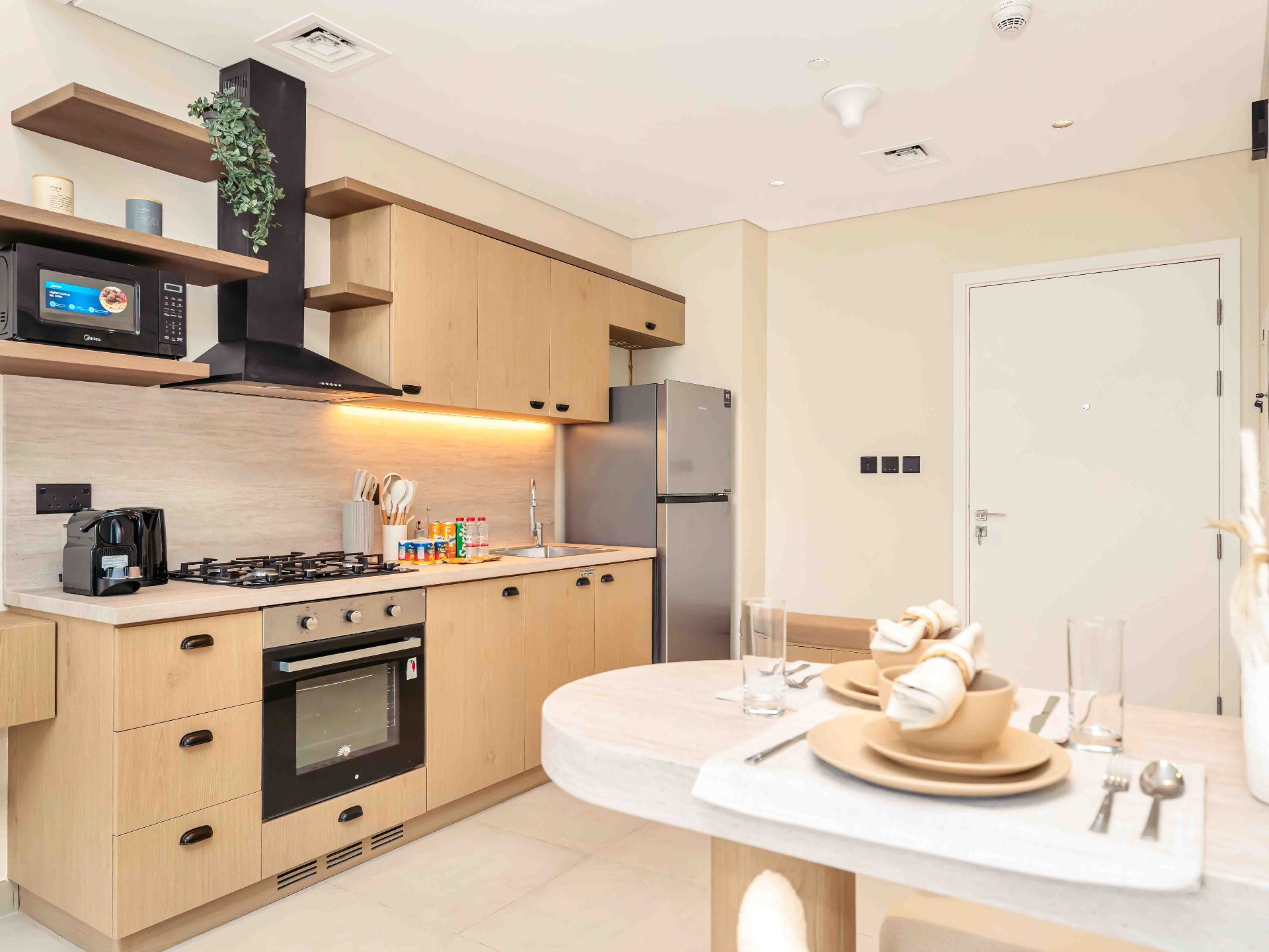 Compact oak kitchen with stone counter, gas hob, integrated oven and open shelving