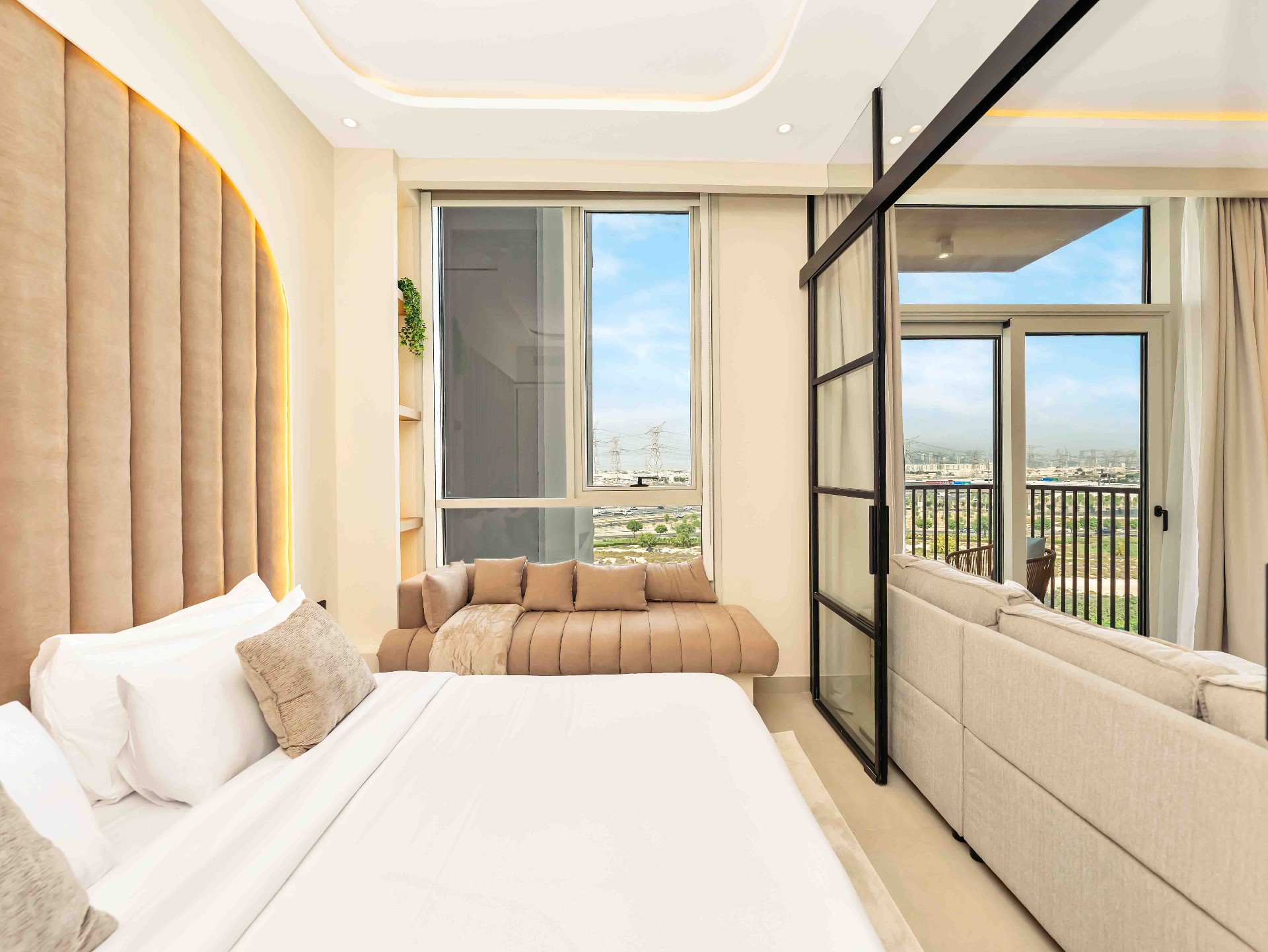Bedroom with arched fluted headboard, window daybed and steel-framed glass partition to living area