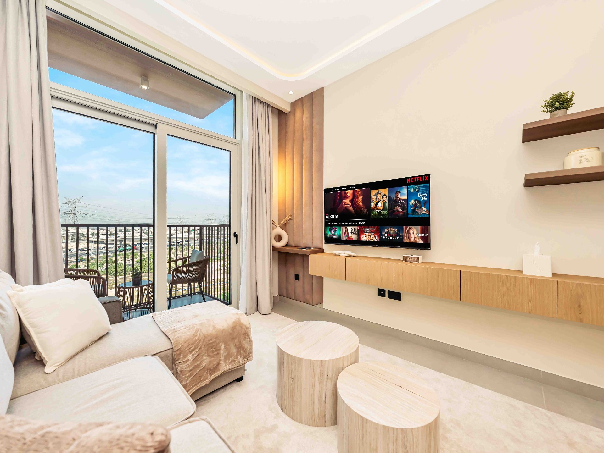 Living room with bespoke floating oak TV wall, travertine coffee tables and balcony view