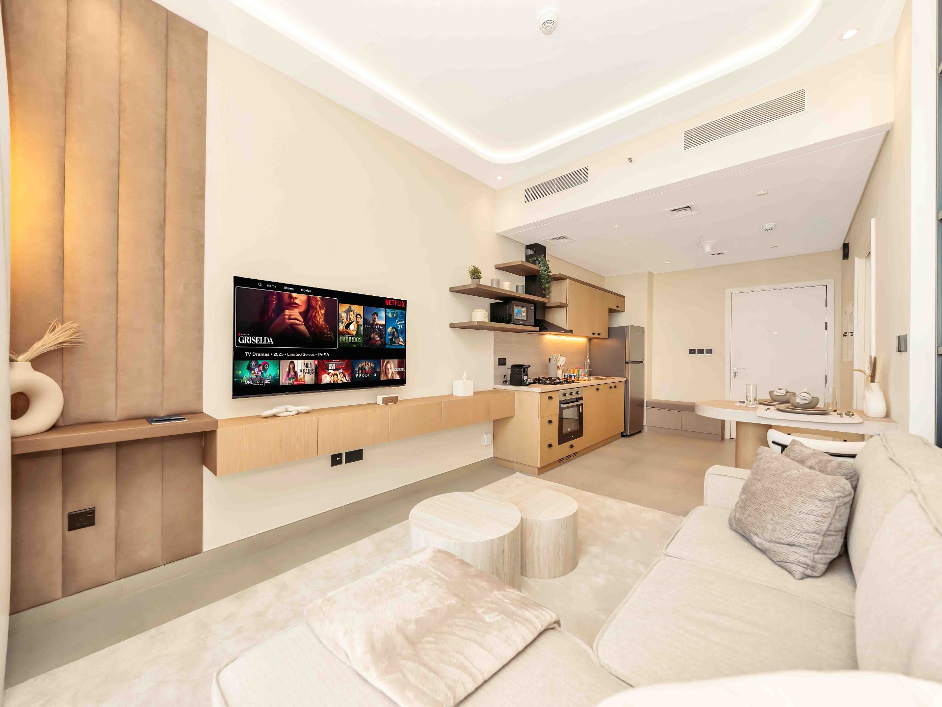 Open-plan living, kitchen and dining with bespoke joinery and warm cove lighting