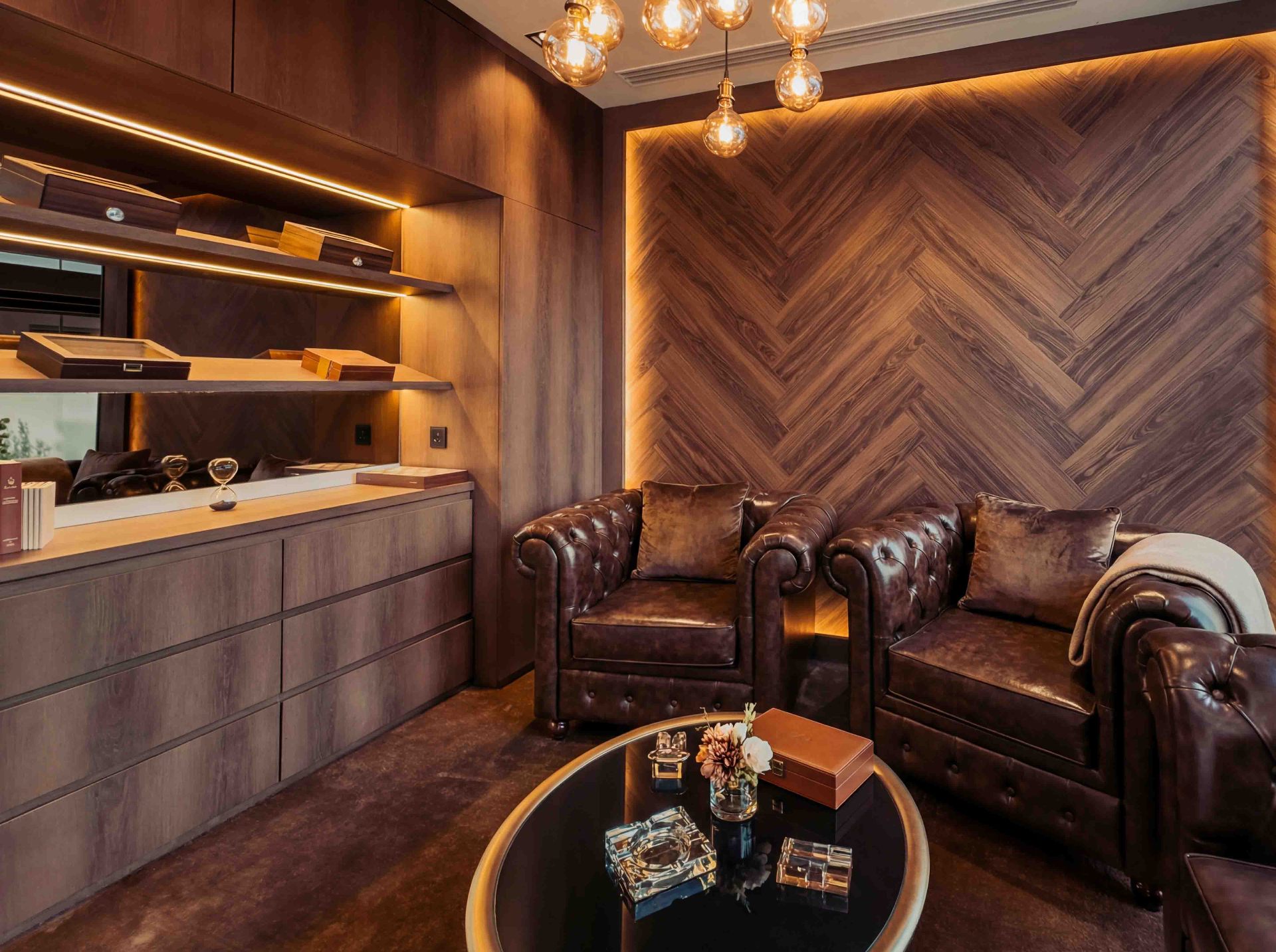 Cigar lounge with herringbone timber wall, Chesterfield armchairs and integrated lighting