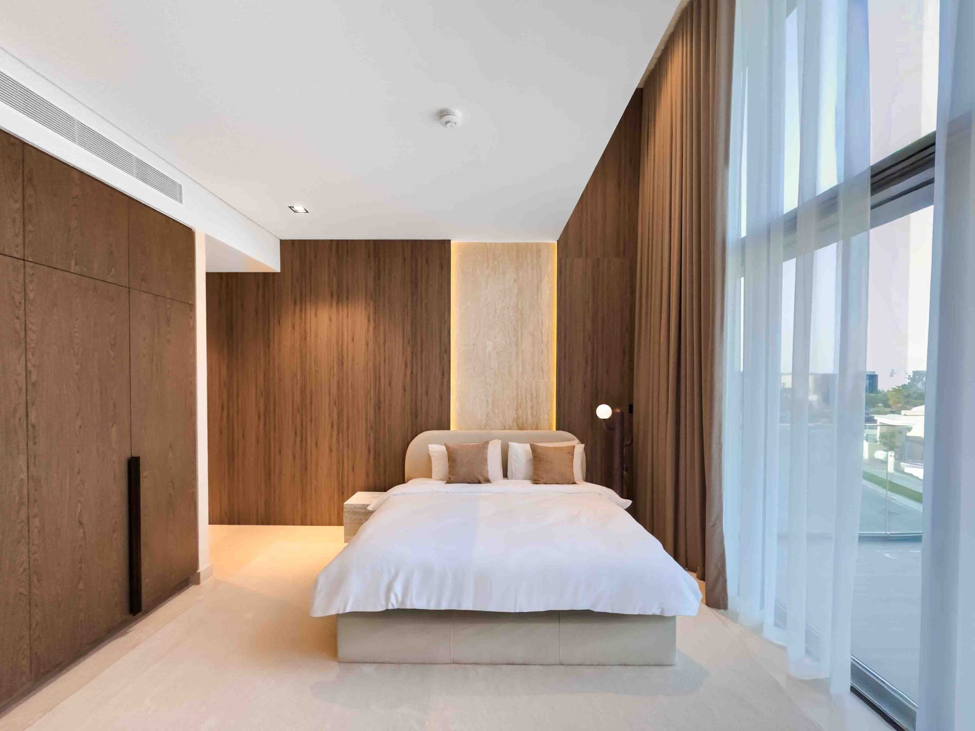 Bedroom with full-height oak panelling and backlit travertine headboard niche