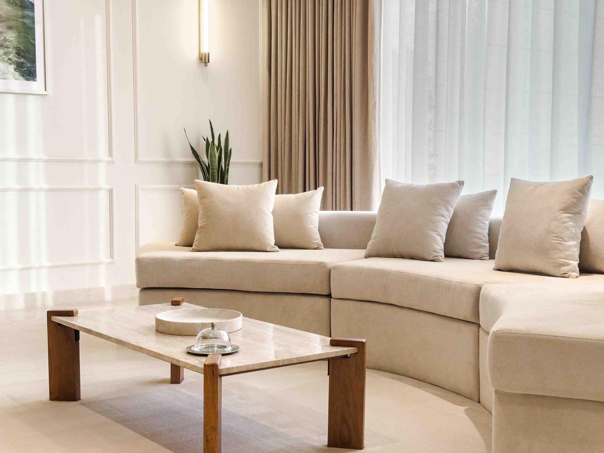 Sitting area with curved cream sofa, marble coffee table and panelled walls