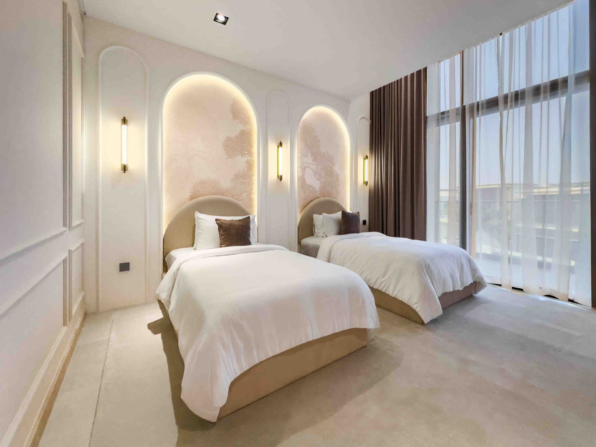 Twin guest bedroom with arched plaster niches and brass wall sconces