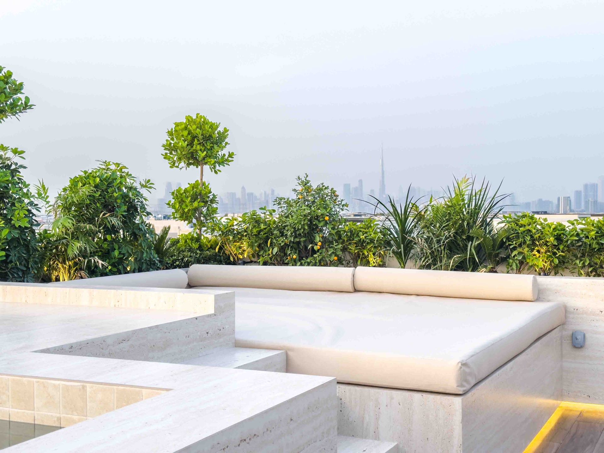 Rooftop lounge with built-in travertine seating and Burj Khalifa skyline view