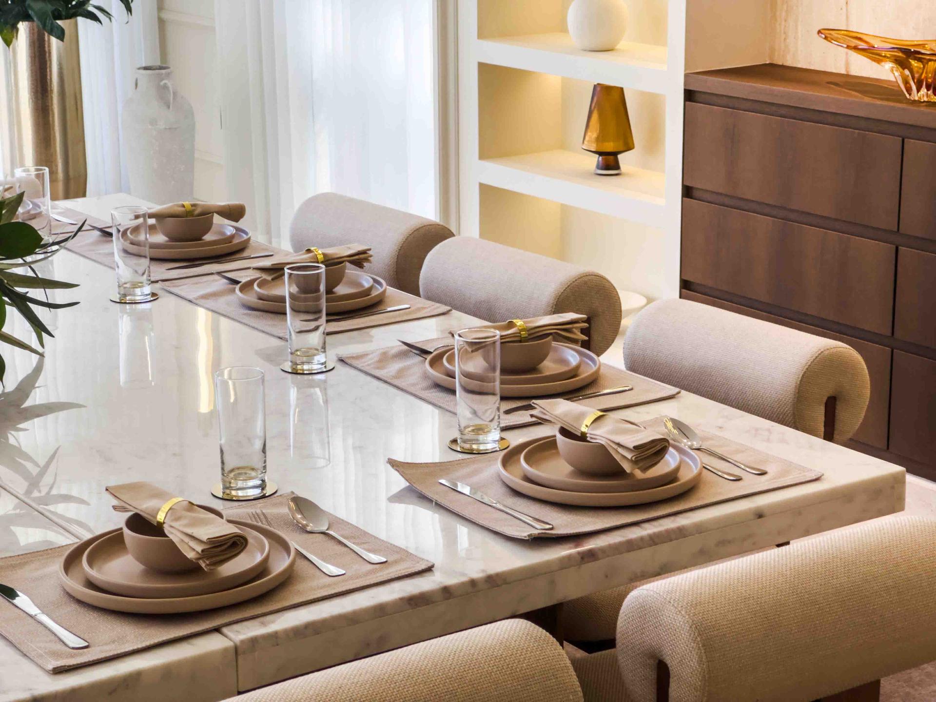 Formal dining table set with marble top, linen runners and bouclé bolster chairs