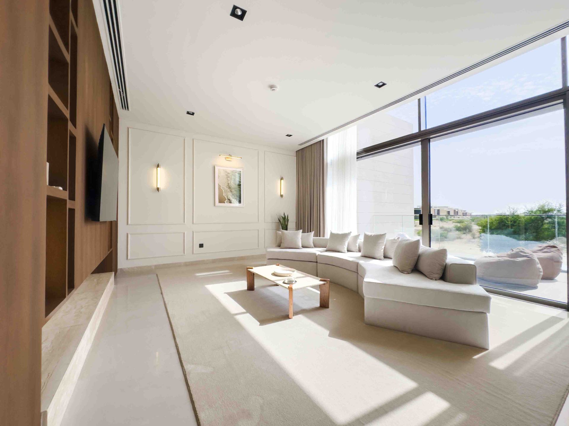 Upstairs family lounge with curved cream sofa, panelled walls and full-height window