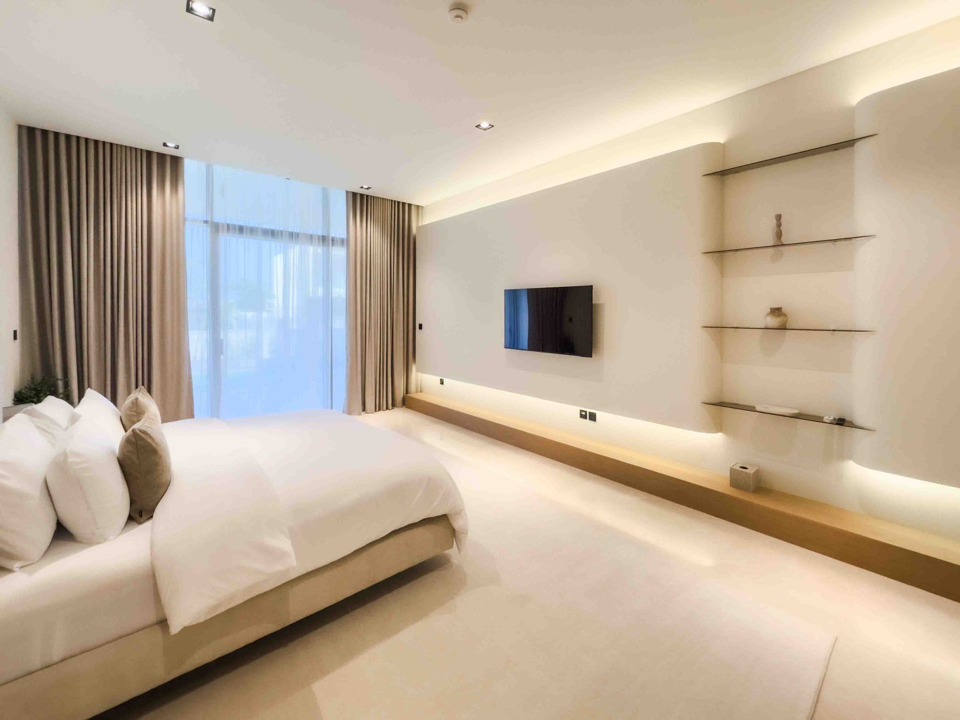 Primary bedroom with floating oak TV console and cove lighting
