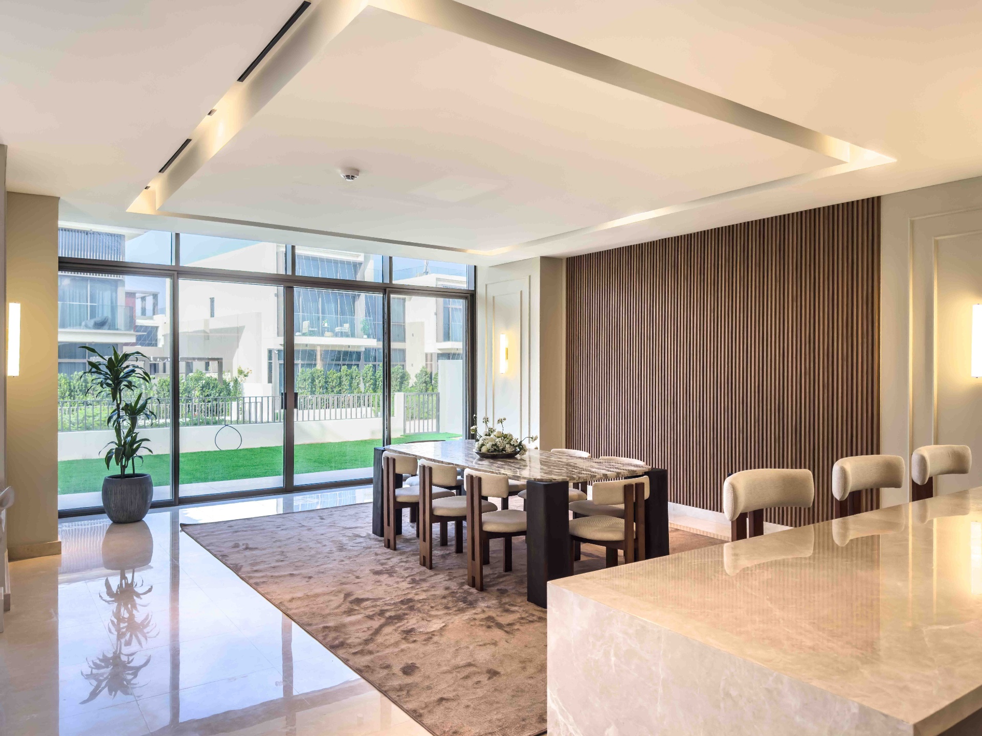 Open-plan dining area with marble table, bouclé chairs and timber slat feature wall