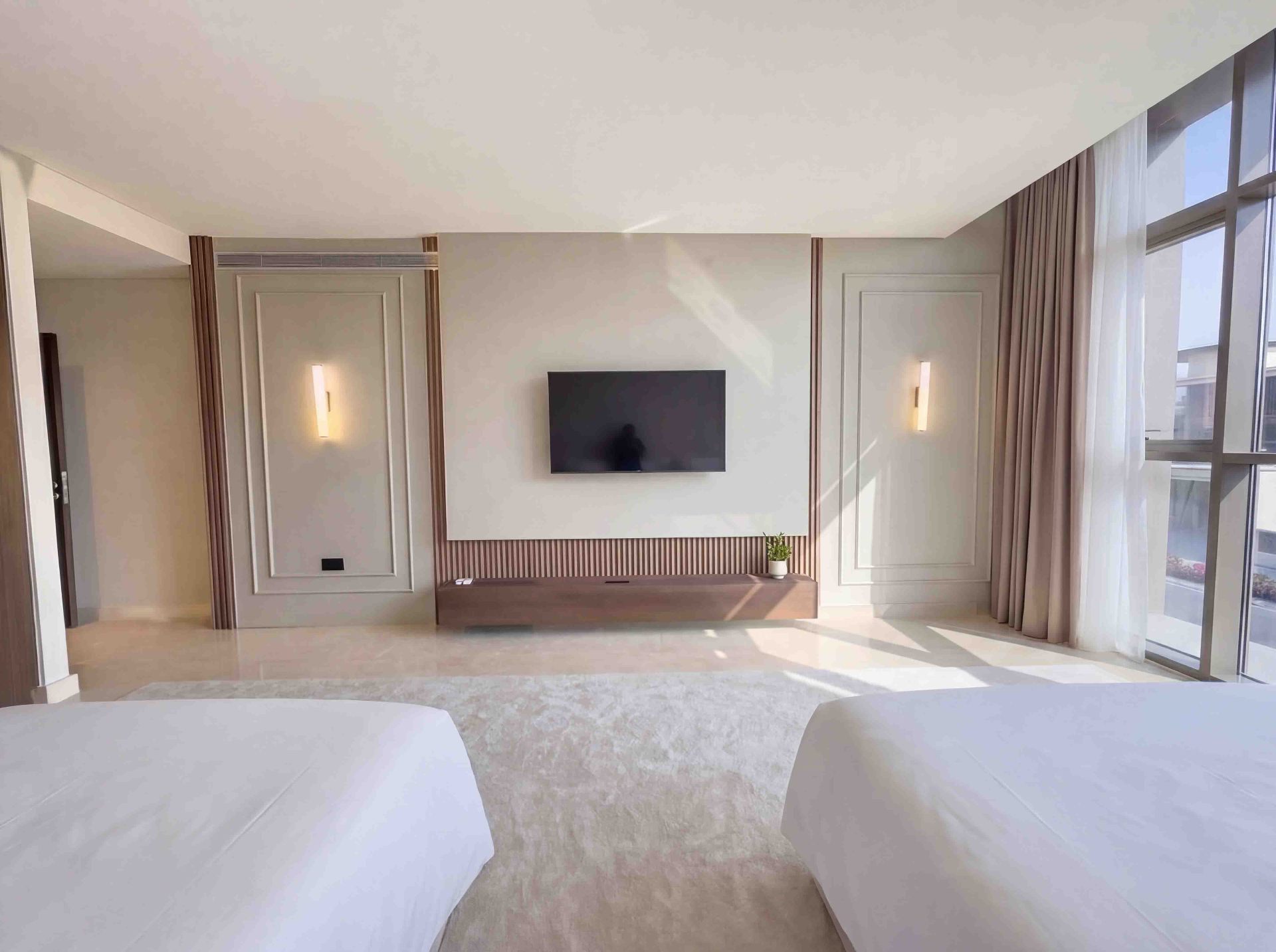 Twin bedroom with panelled TV wall, fluted timber accents and warm wall sconces