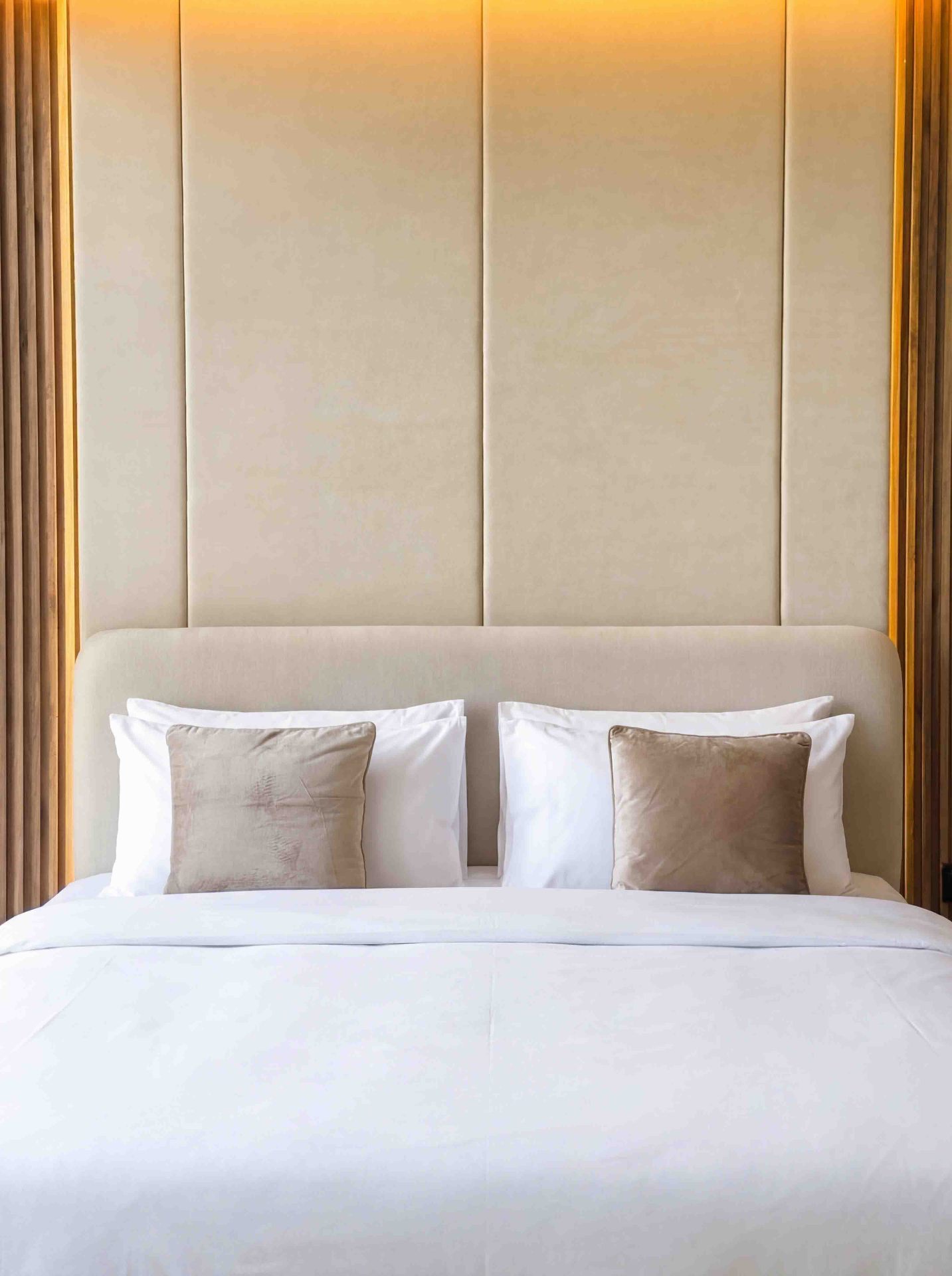 Bedroom with channel-tufted upholstered headboard and backlit timber frame
