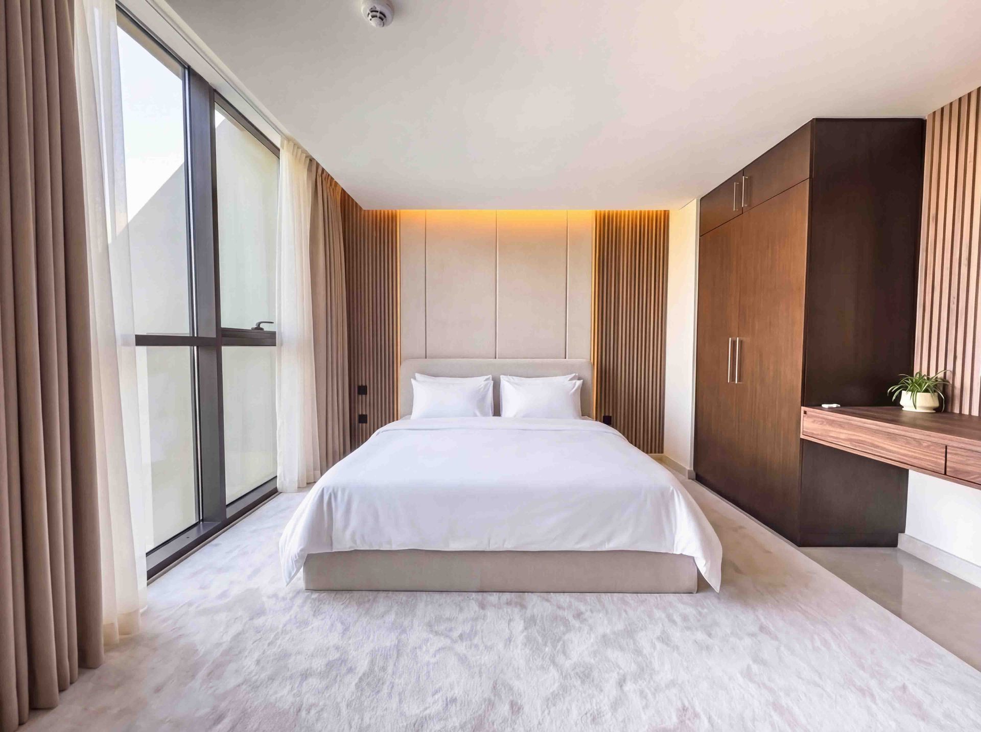 Bedroom with fluted timber headboard wall, integrated wardrobe and desk