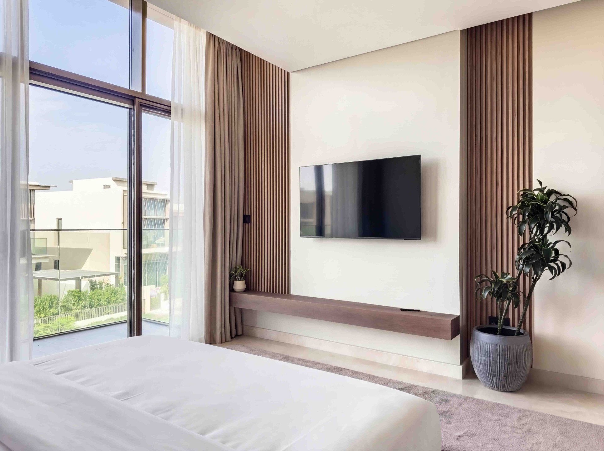 Bedroom TV wall with fluted oak panelling, floating timber shelf and full-height window