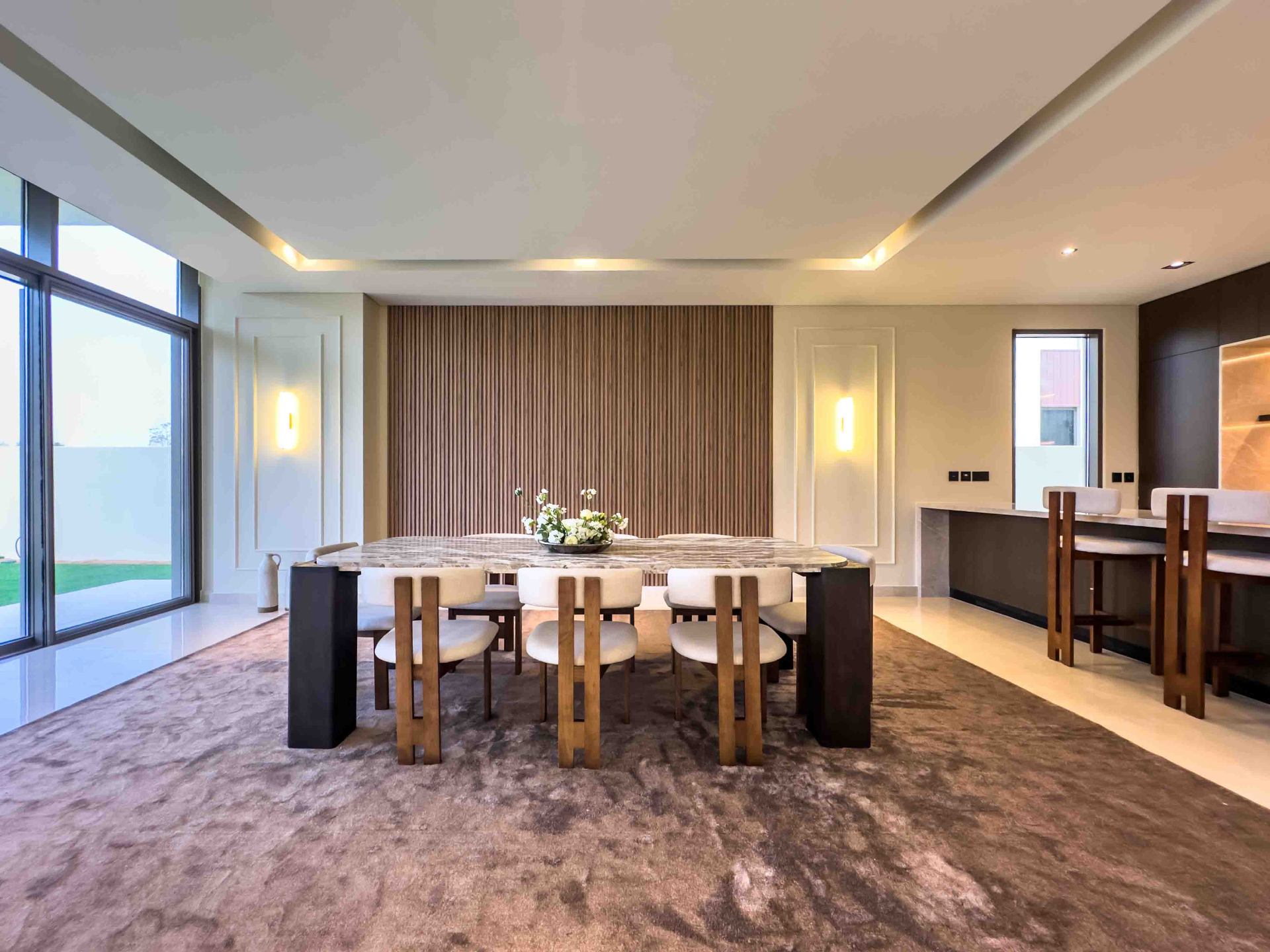 Dining room with sculptural marble table, wall sconces and timber slat panelling