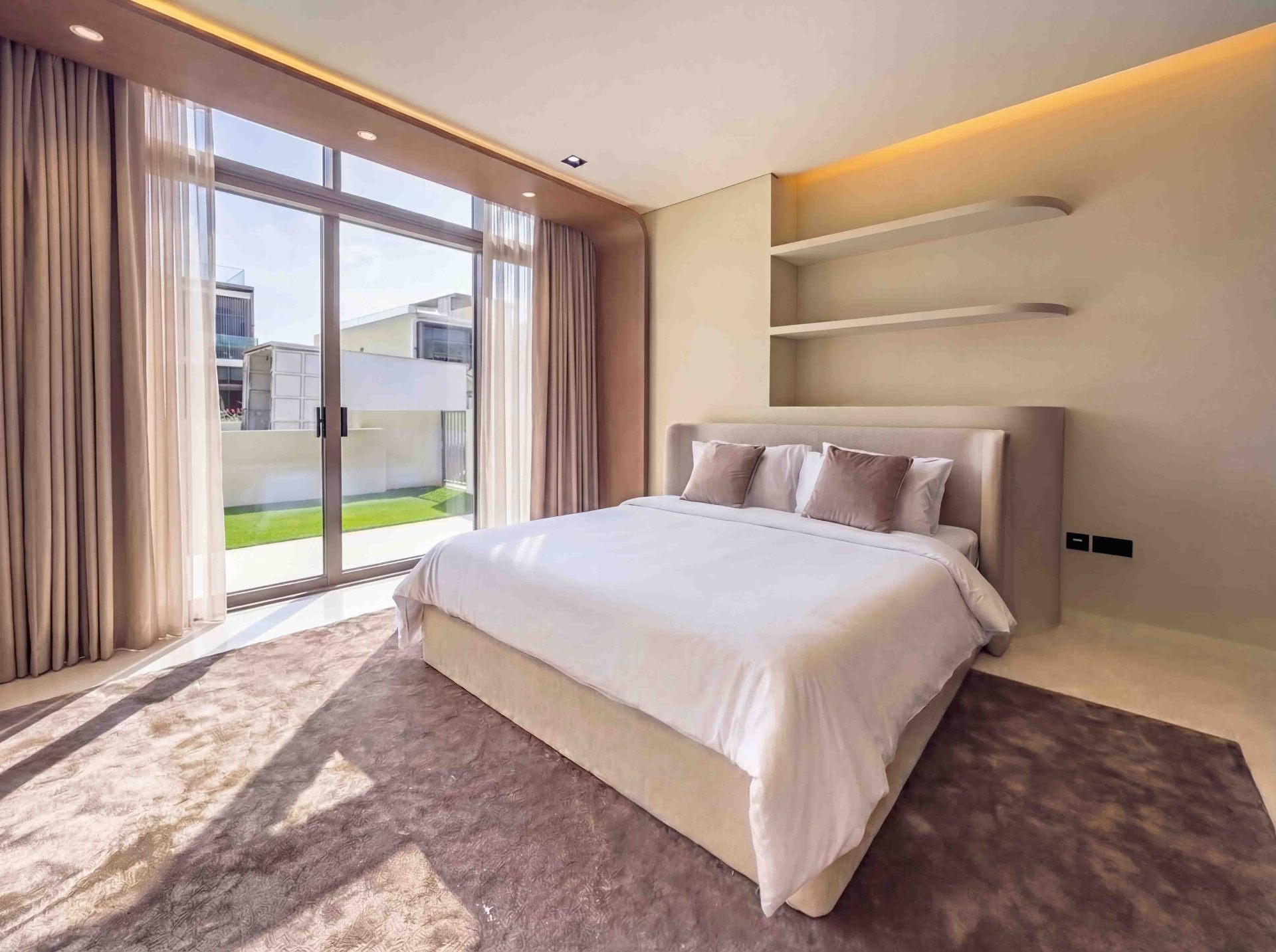 Guest bedroom with cove lighting, floating shelves and floor-to-ceiling sheers
