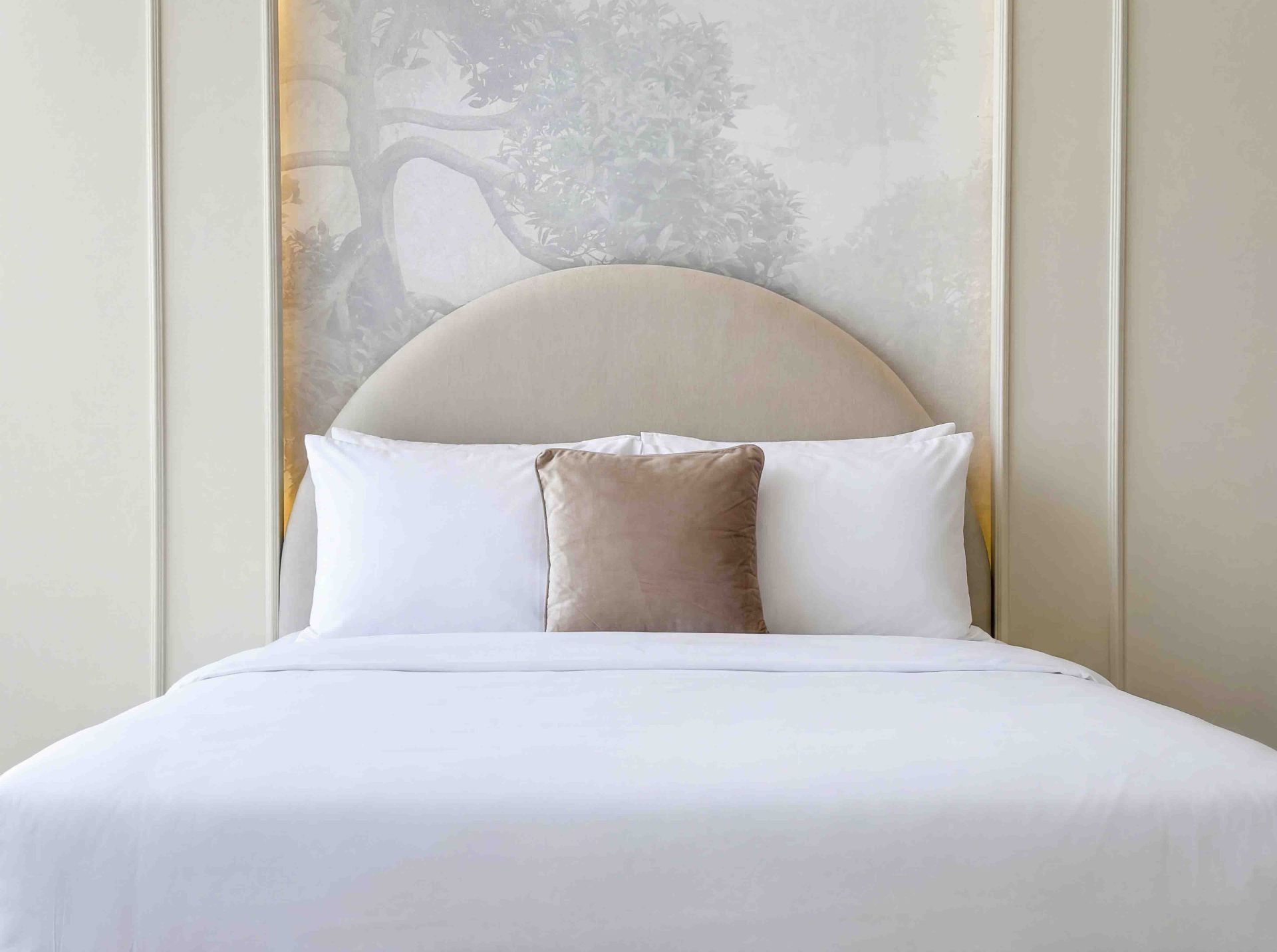 Bedroom with curved upholstered headboard and hand-painted forest wall mural
