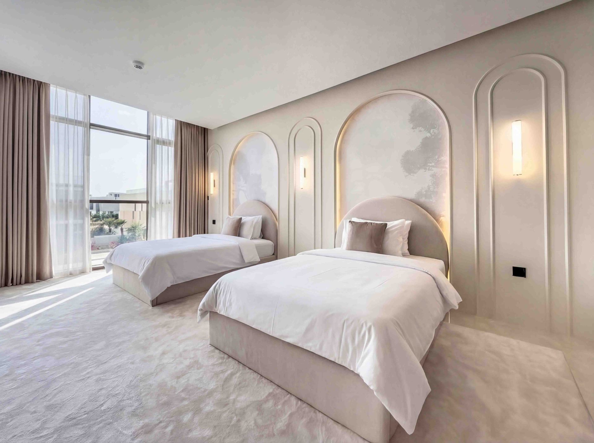 Twin guest bedroom with arched plaster niches and soft wall sconces