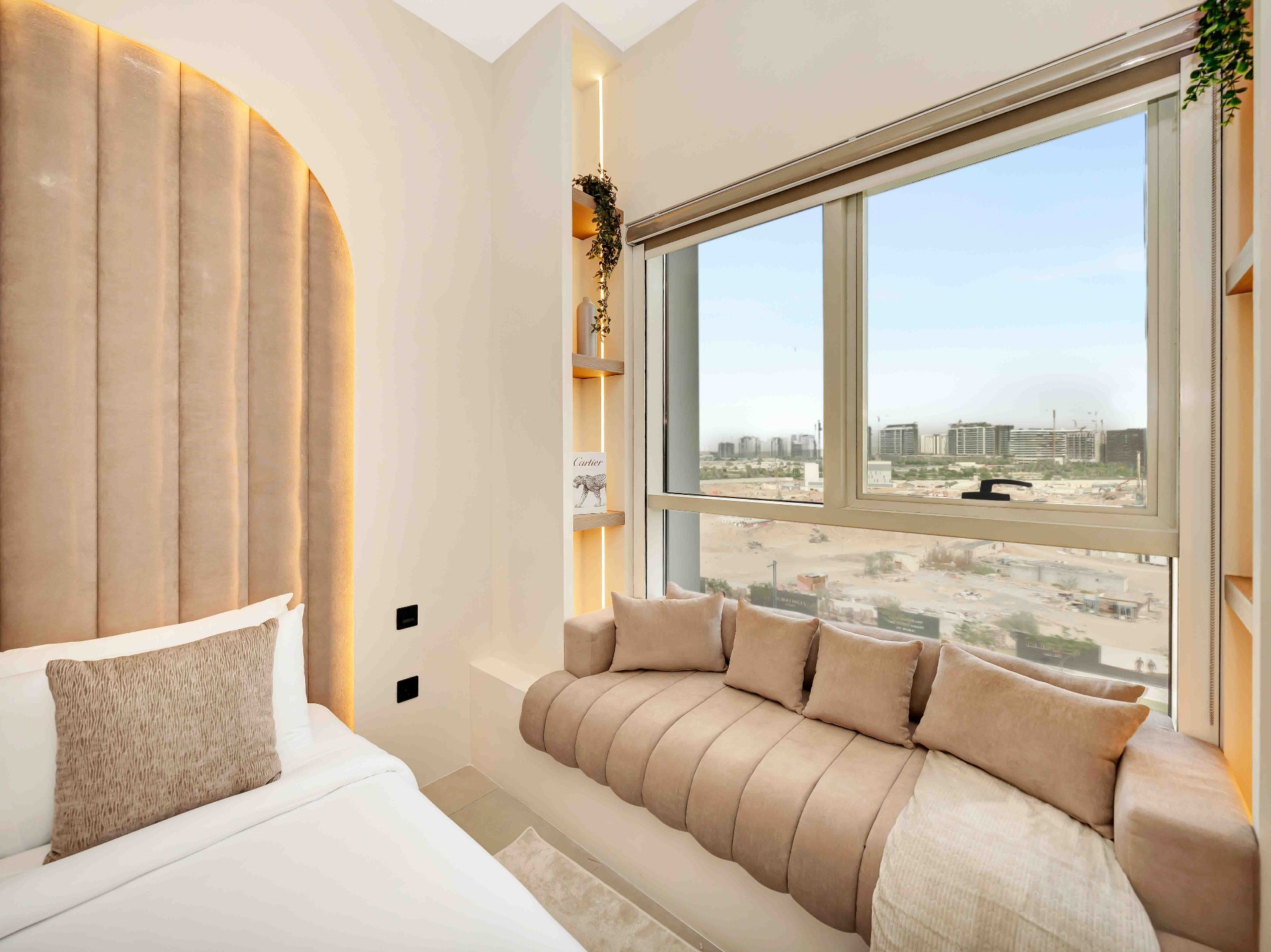 Bedroom with arched fluted headboard, upholstered window daybed and styled recessed shelving