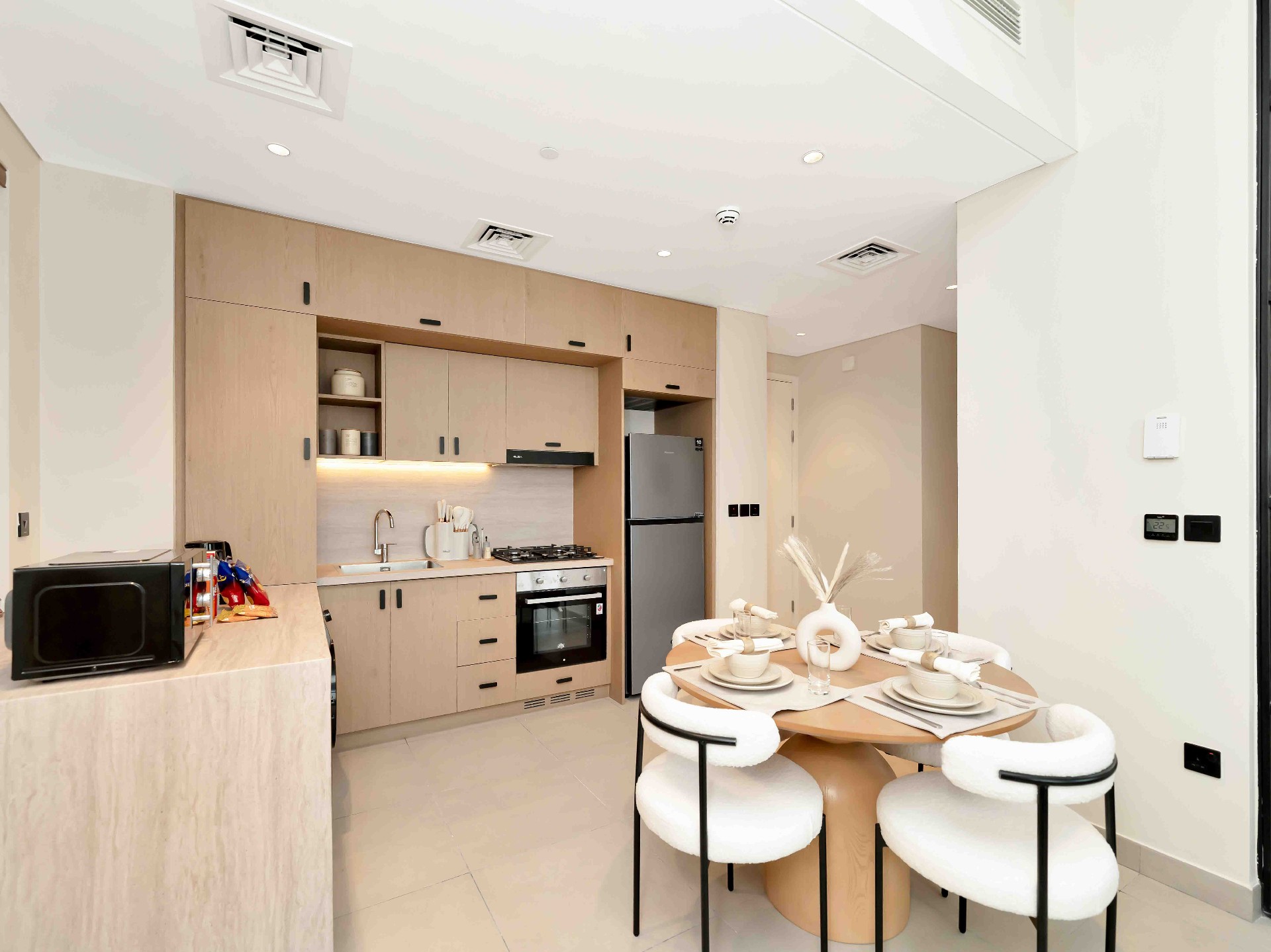 Oak kitchen with stone counter, gas hob, integrated oven and travertine dining table with boucle chairs