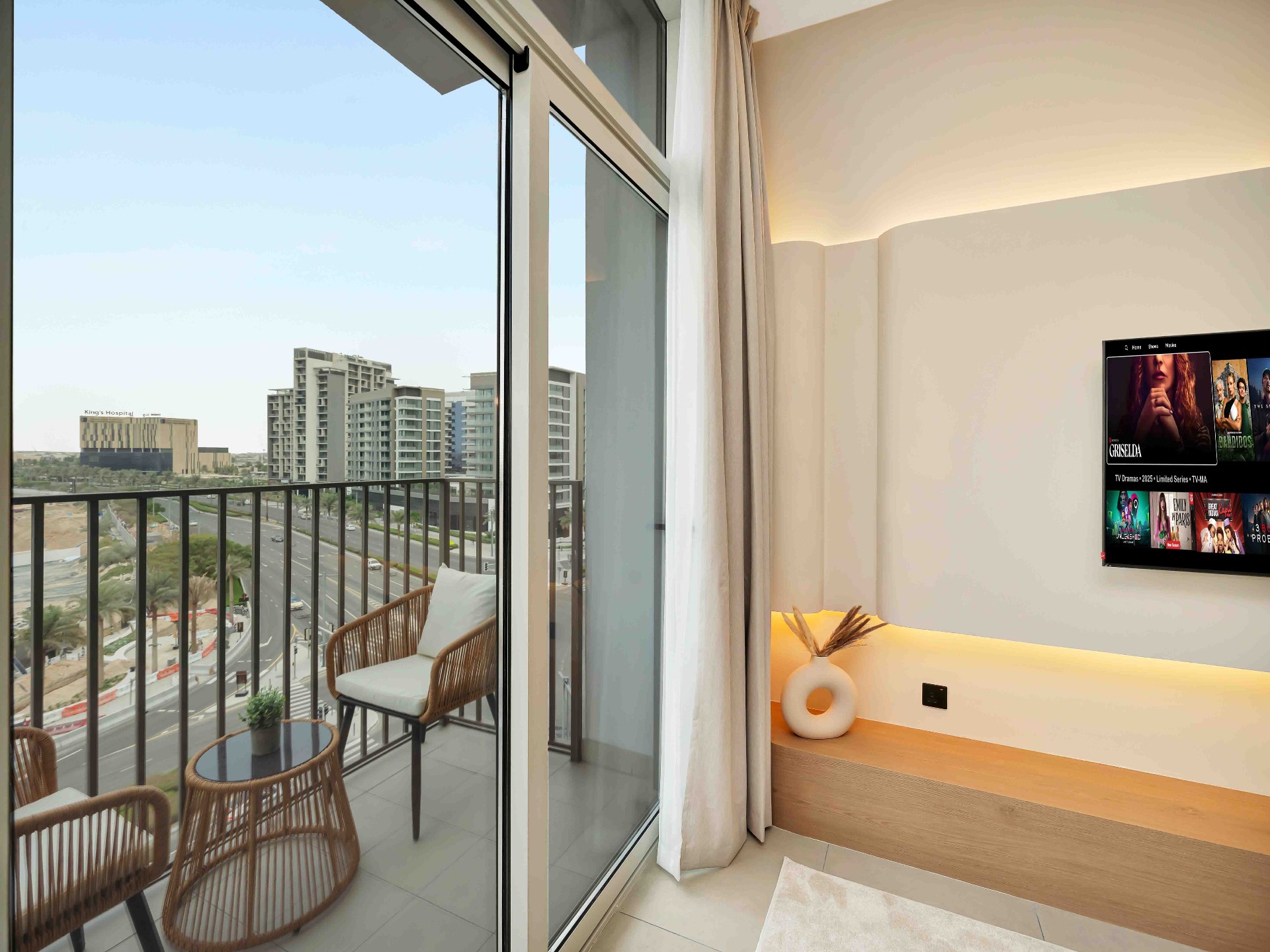 Balcony with rattan chairs and side table beside a floating oak bench and cove-lit feature wall